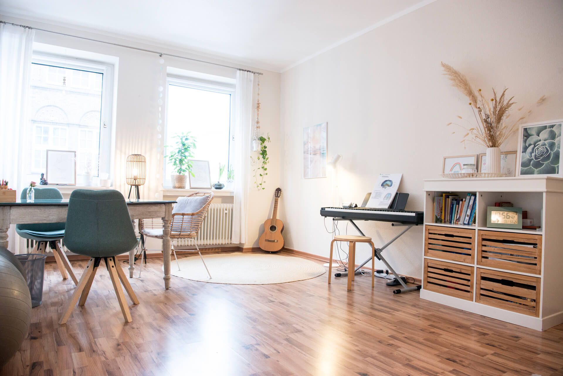 Heller Therapieraum mit Tisch, Klavier, Gitarre und Holzboden